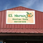 Printed sign installed above store in small shopping strip. El Naranjo mexican store