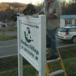 Signs by Design worker finalizing install of custom solar lighting rig. Installing lighting rig